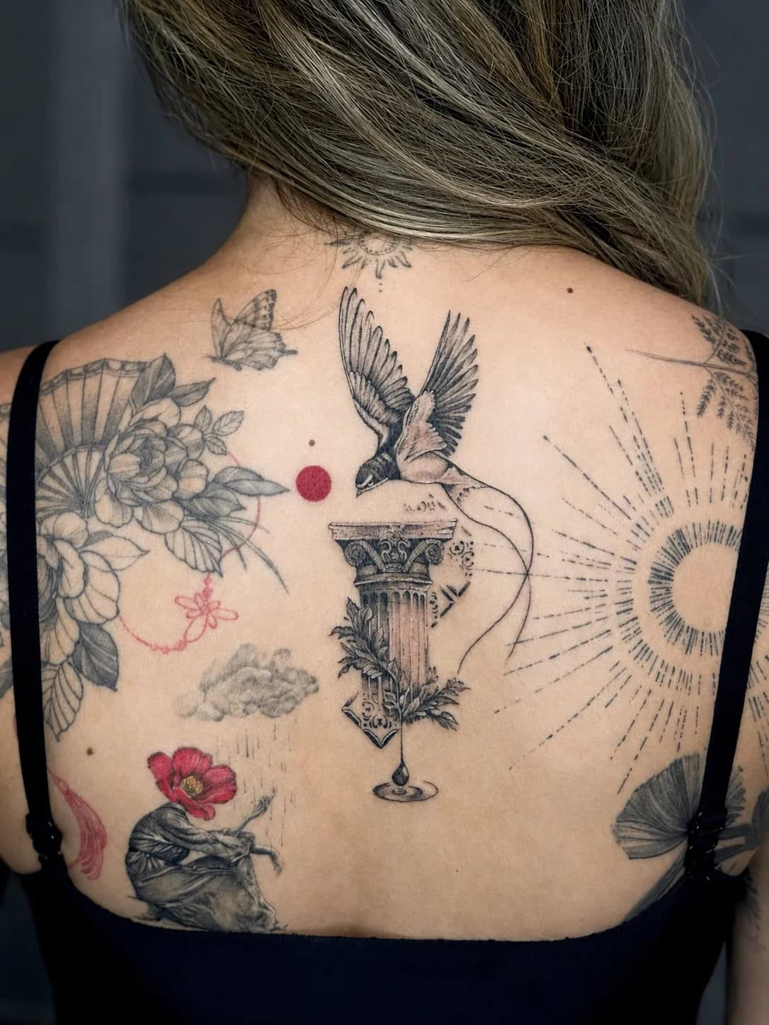Tatuaj alb-negru pe spate cu o coloană antică și o rândunică în zbor