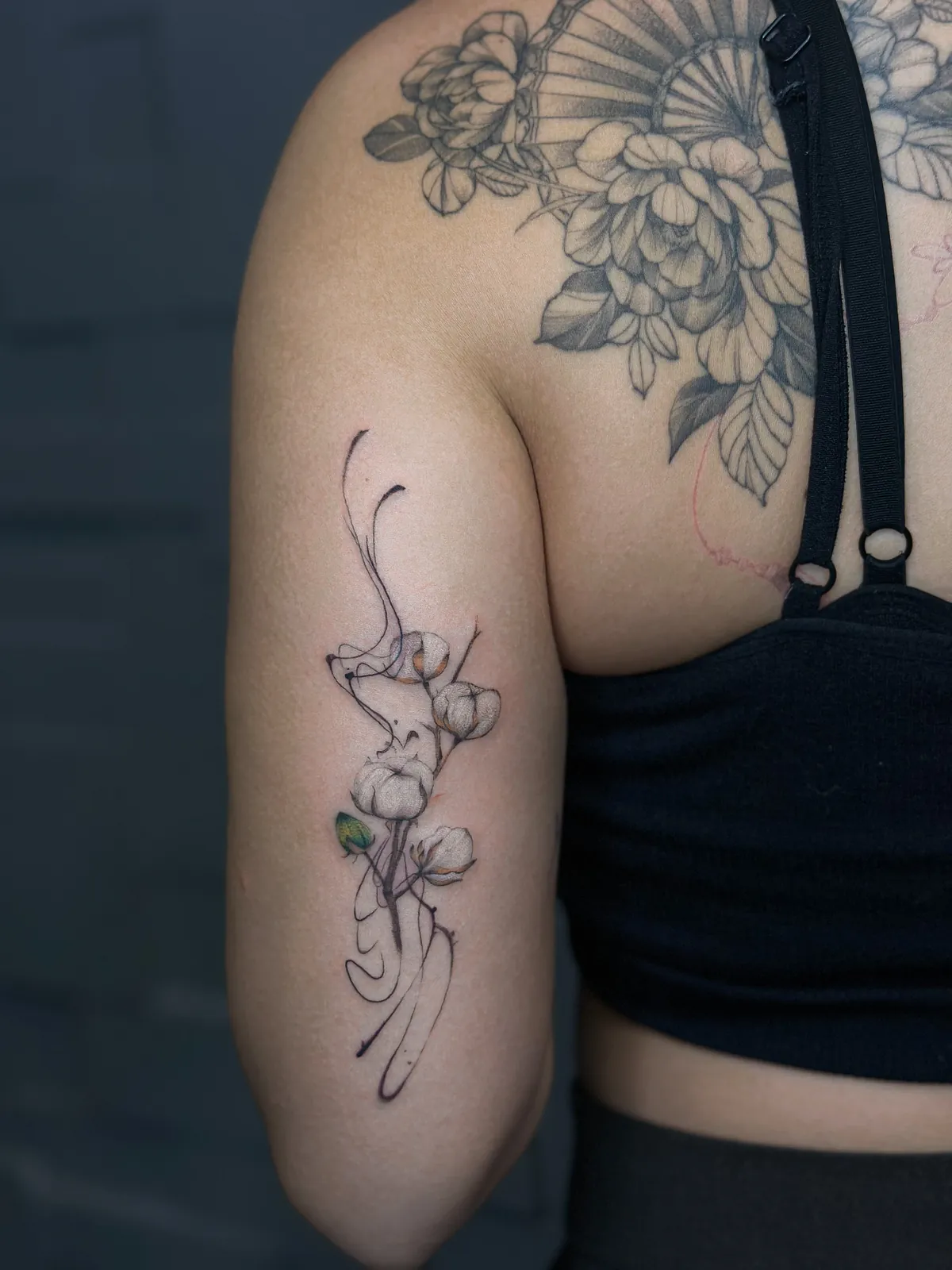 Tatuaj fine line pe braț cu o creangă cu flori de bumbac