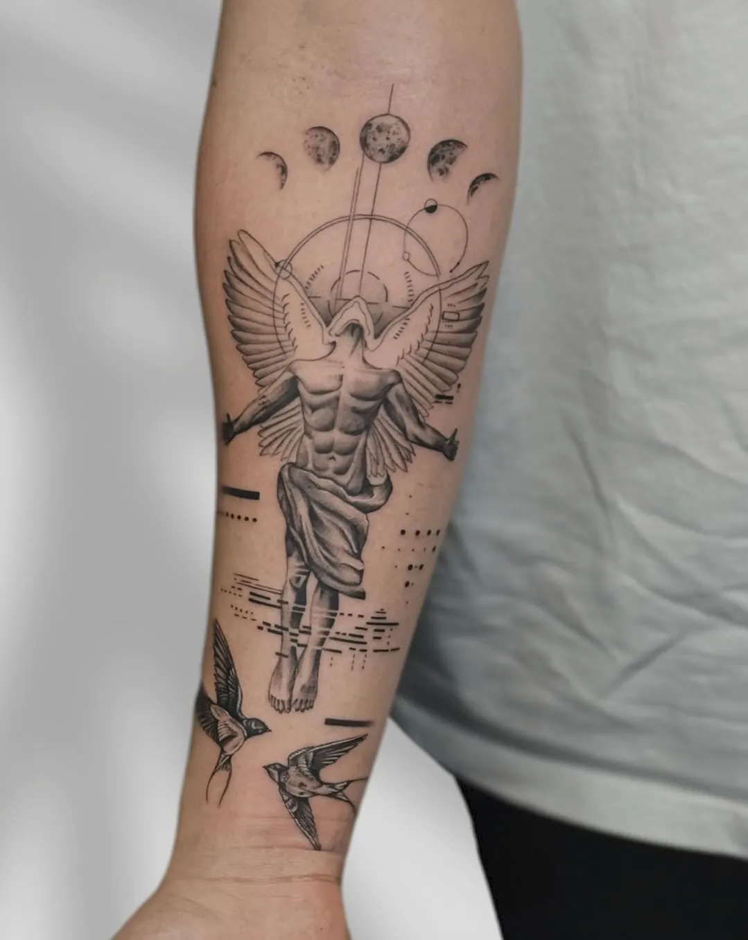 Tatuaj alb-negru pe antebraț cu un înger fără chip, fazele lunii și rândunele