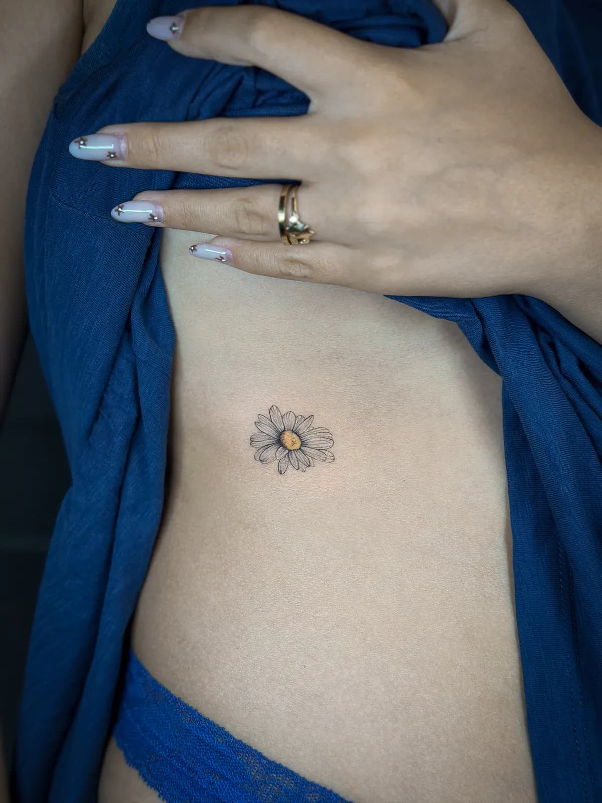 Tatuaj fine line pe coaste cu o margaretă mică