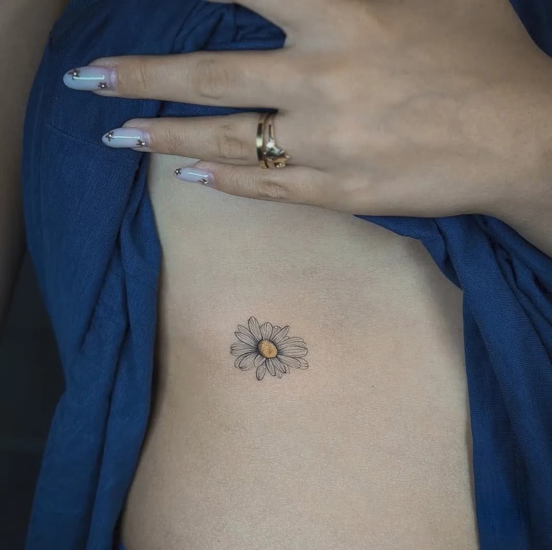 Tatuaj fine line pe coaste cu o margaretă mică