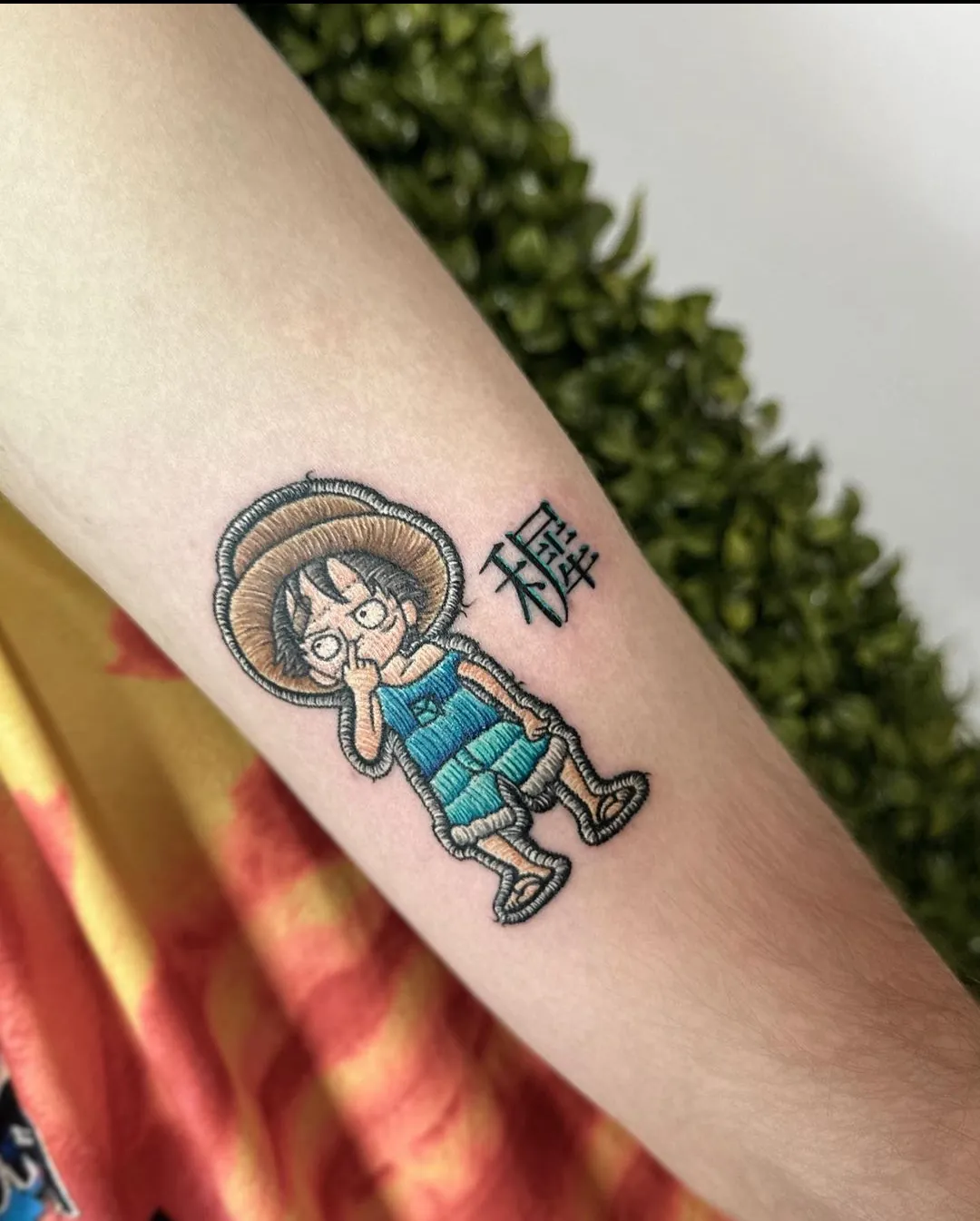 Tatuaj color pe mână cu un personaj anime cu pălărie de paie