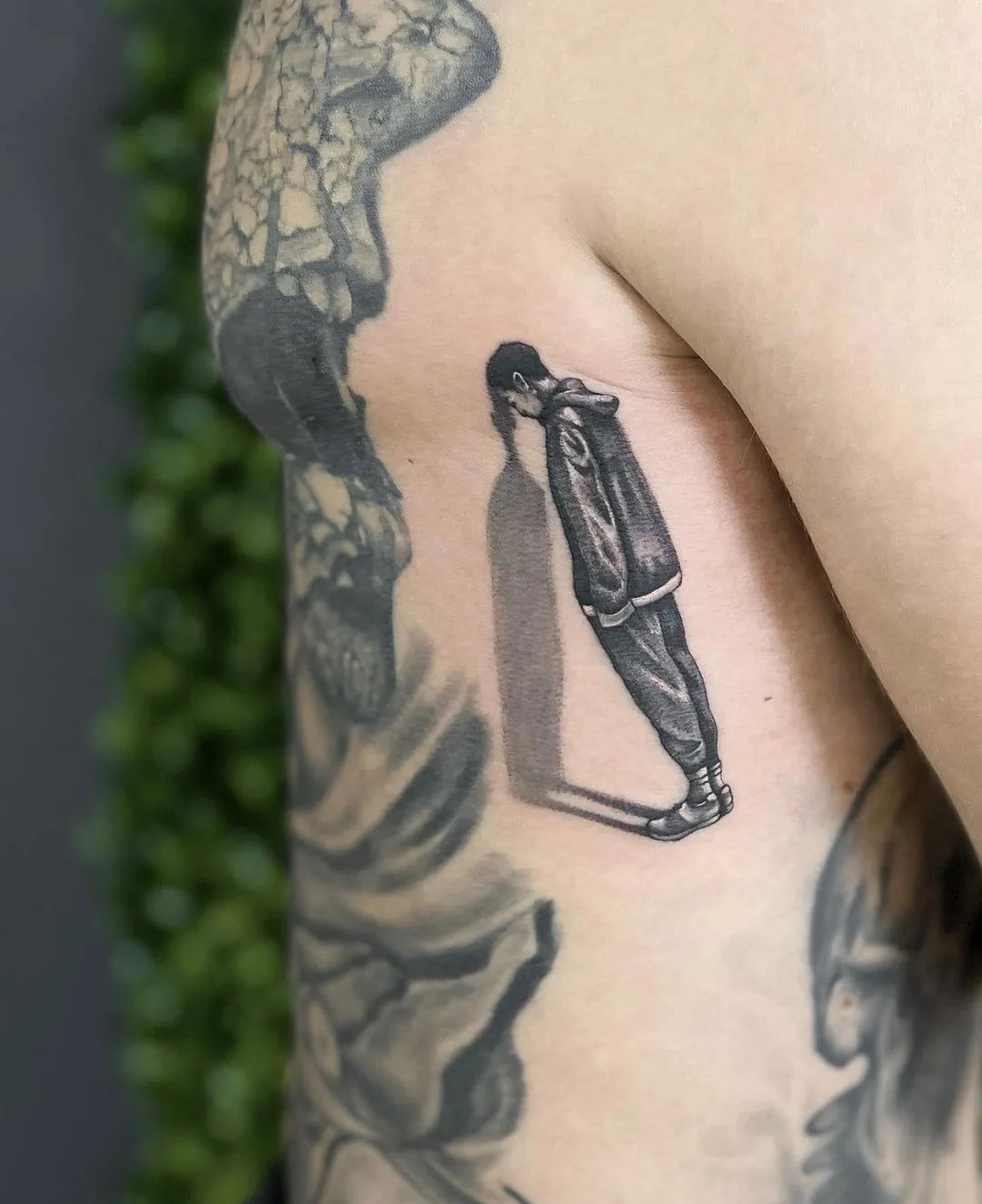 Tatuaj alb-negru pe coaste cu o siluetă într-un cadru