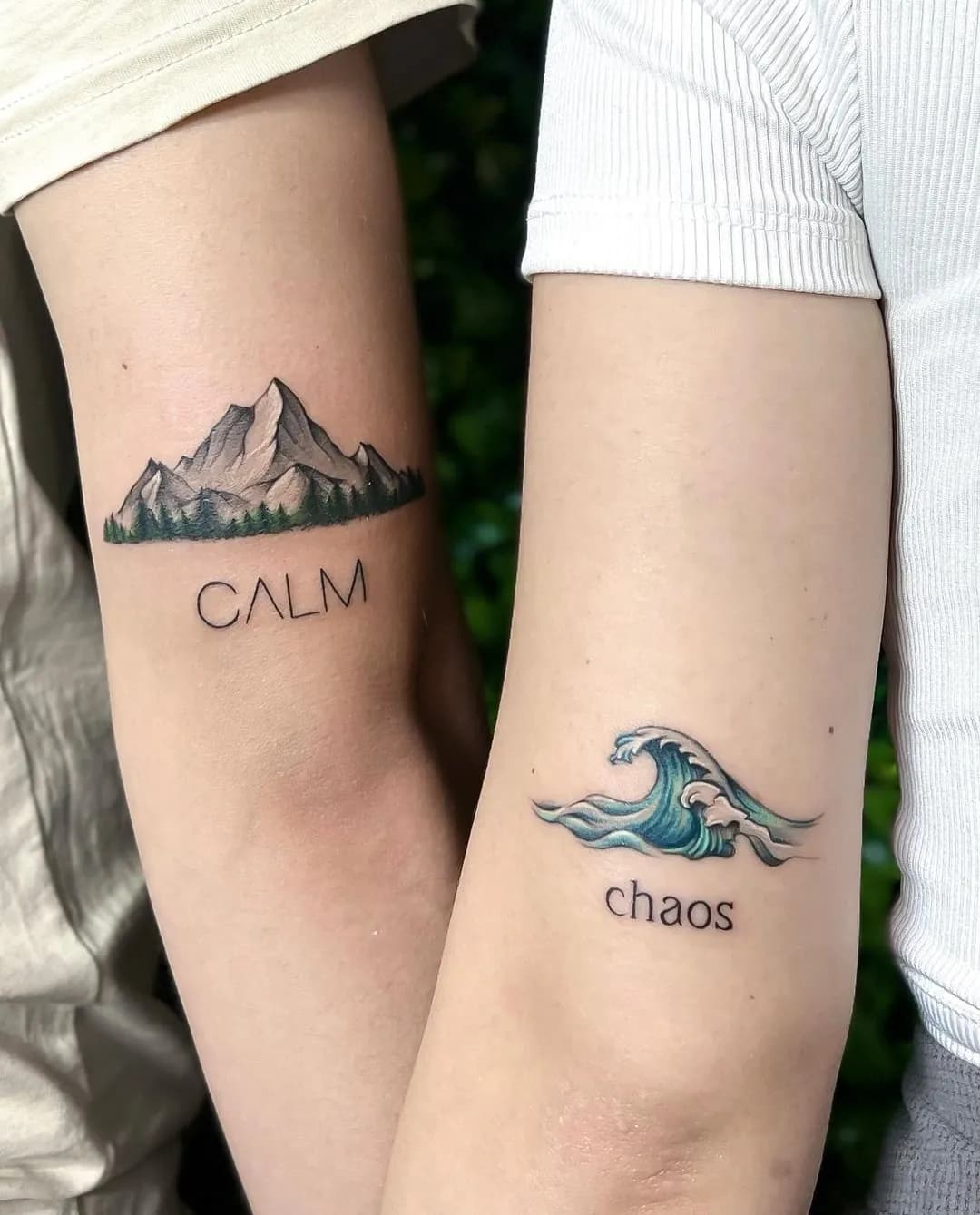 Tatuaje pereche pe antebrațe — munte cu textul CALM și val cu textul chaos